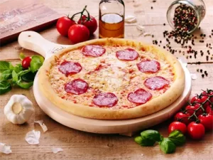 Domača pizza, na kateri je salama, na lesenem podstavku
